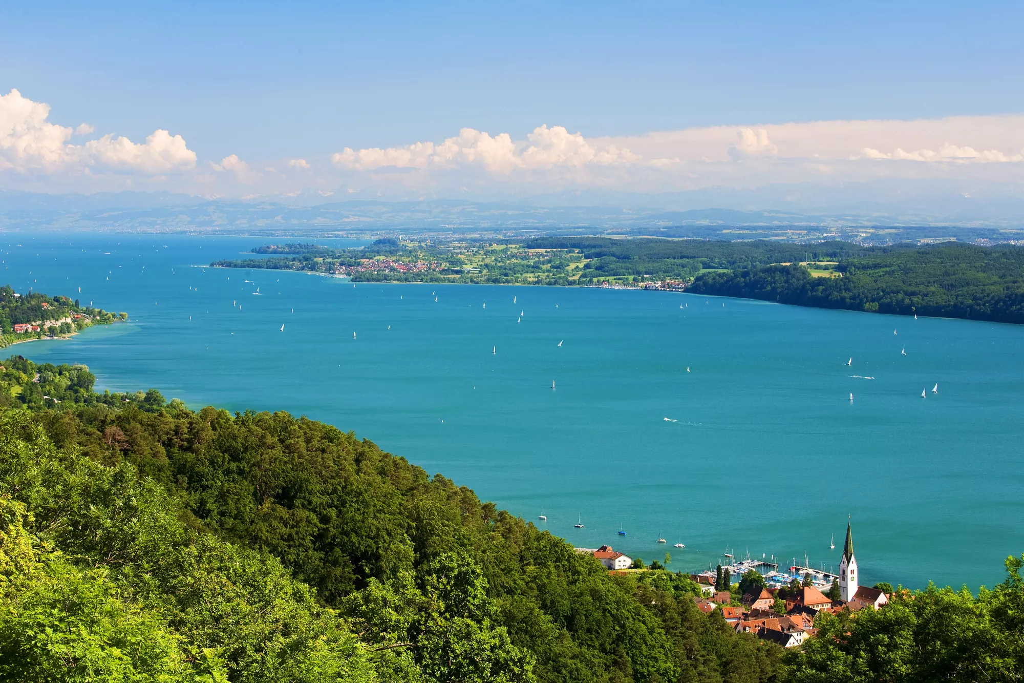 Helderblauw, groot meer. Aan de zijkant groen land en dorpjes