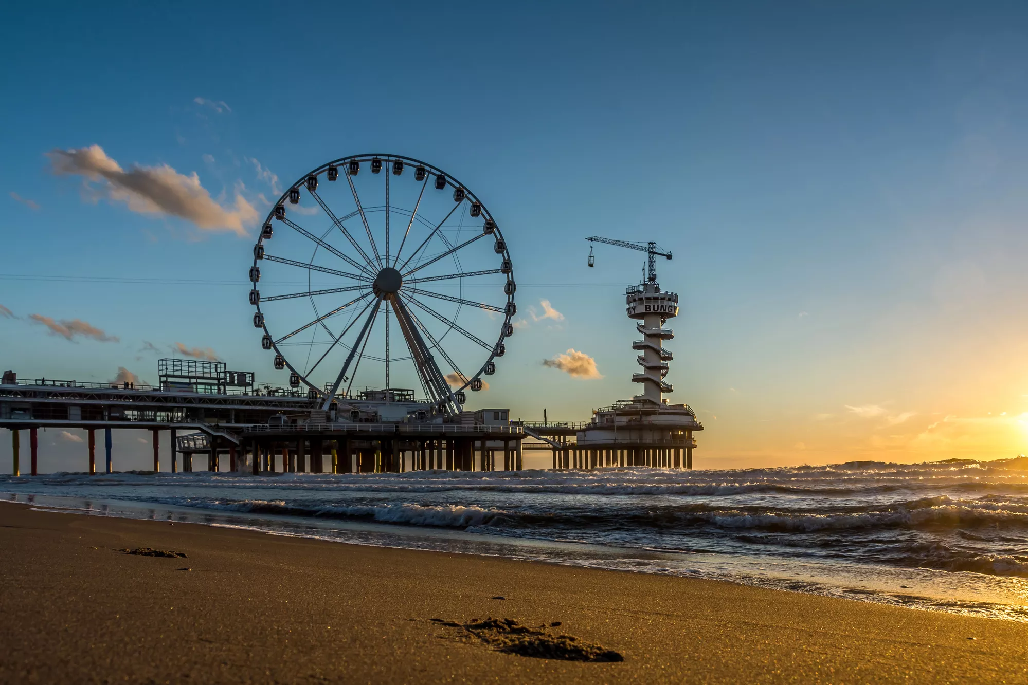 pier aan zee met en reuzenrad en een toren erop