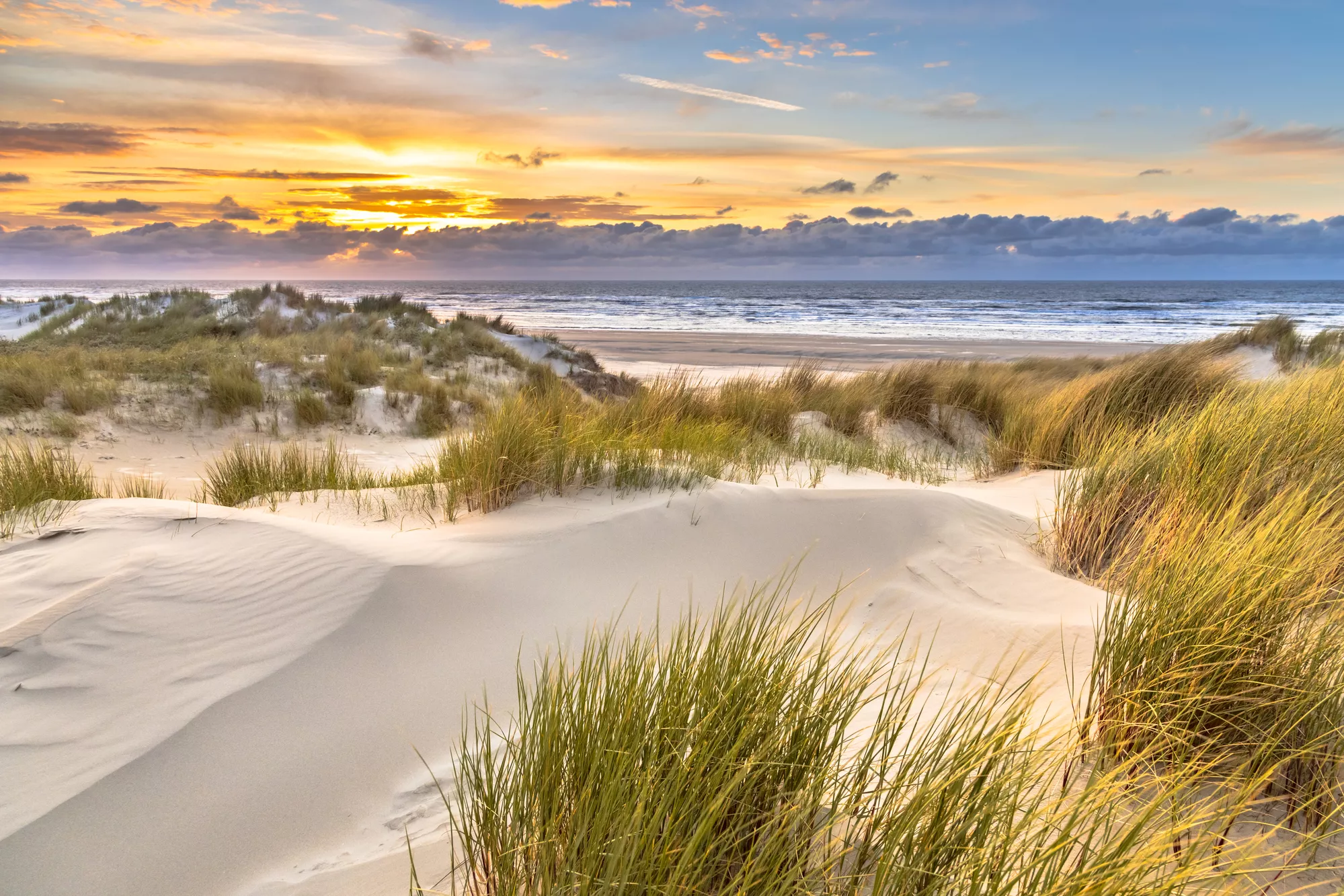 duinen aa nzee met een zonsondergang op de achtergrond