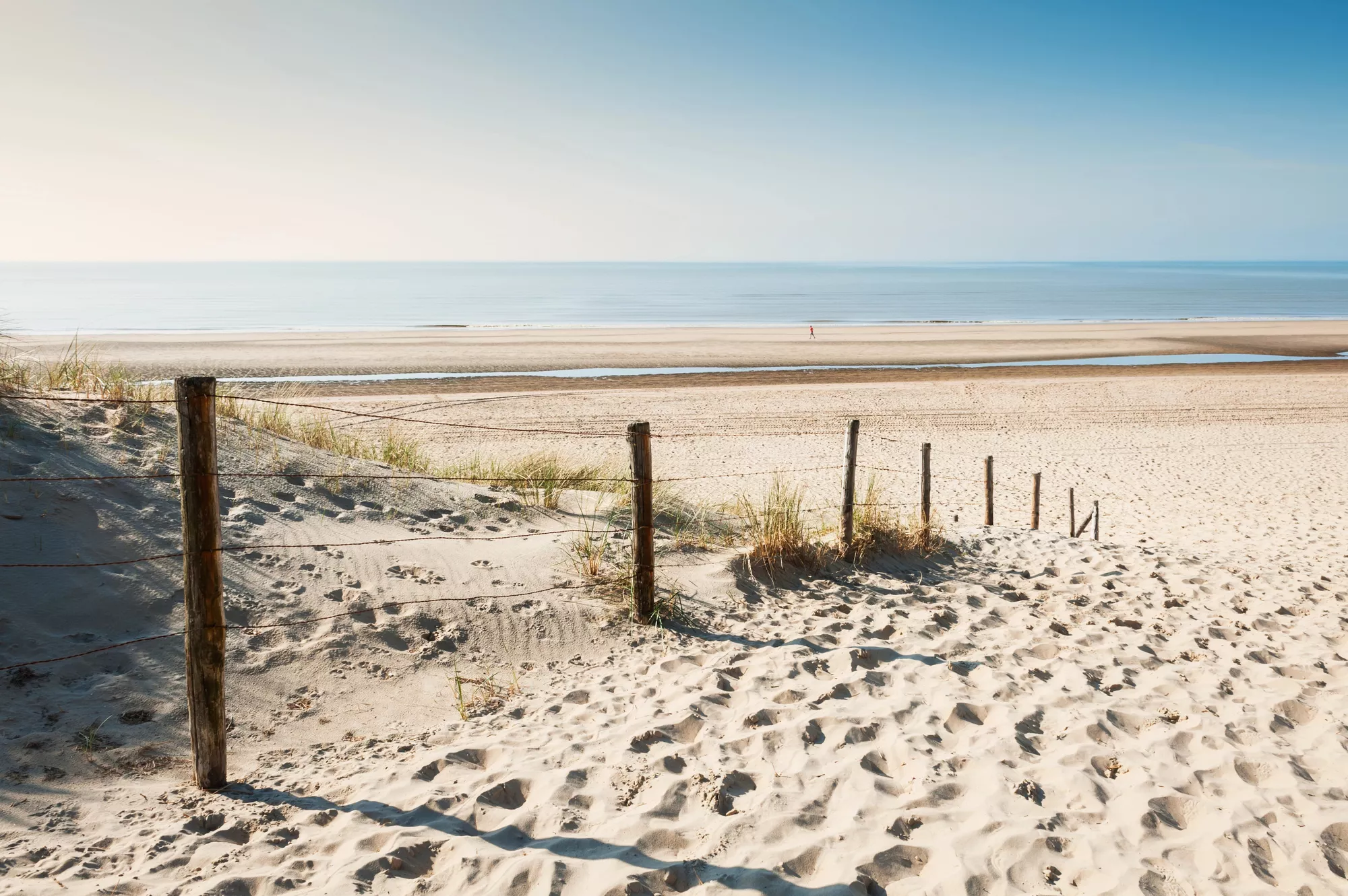 strandopgang, wit strand en een blauwe lucht