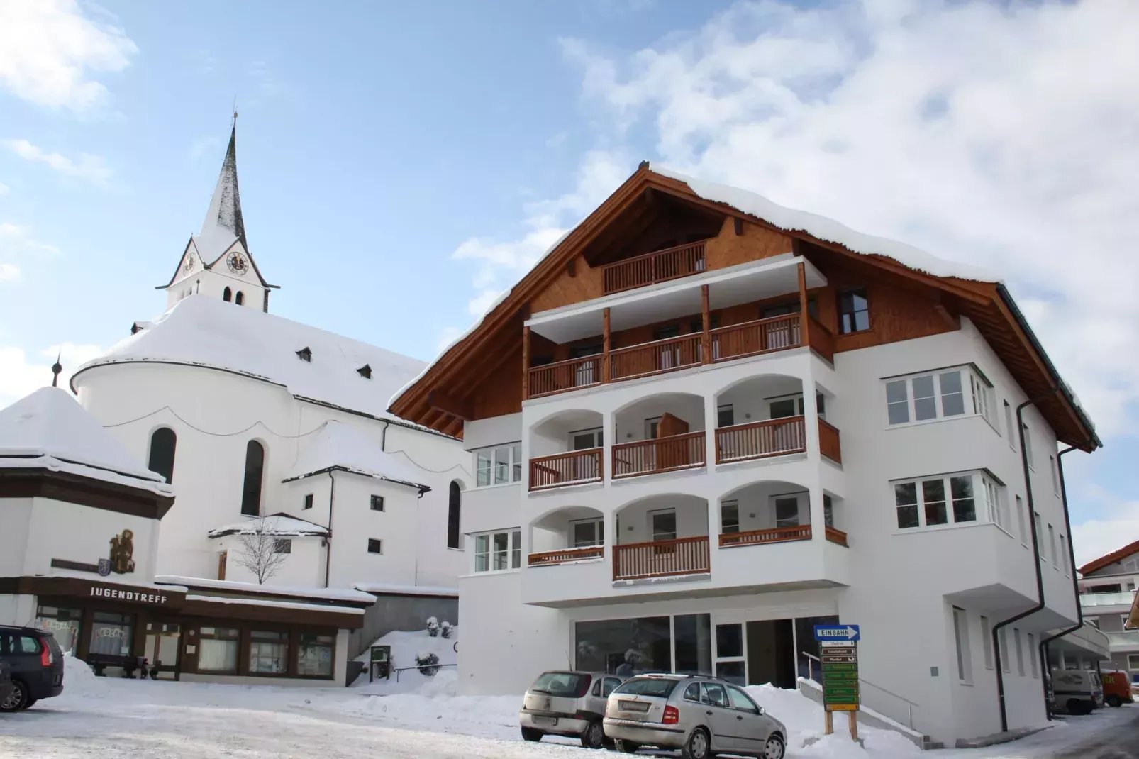 houten balkon bij huis, met kerk op de achtergrond. onder de sneeuw